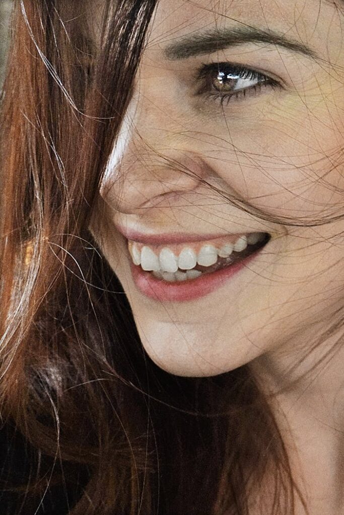 Close-up of a woman smiling with brown hair, capturing joy and natural beauty.