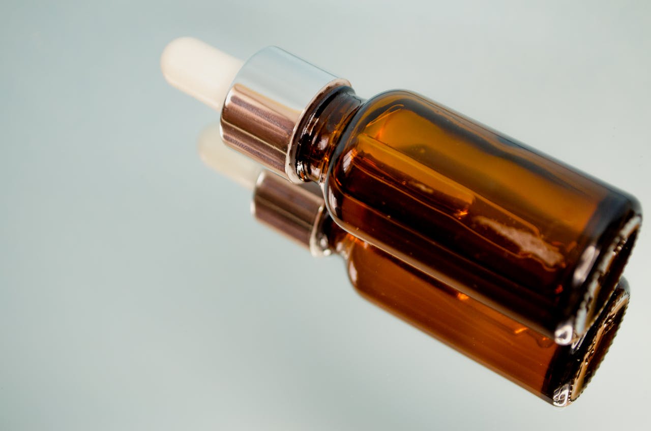 Close-up of a brown dropper bottle reflecting on a glass surface, perfect for skincare or aromatherapy themes.