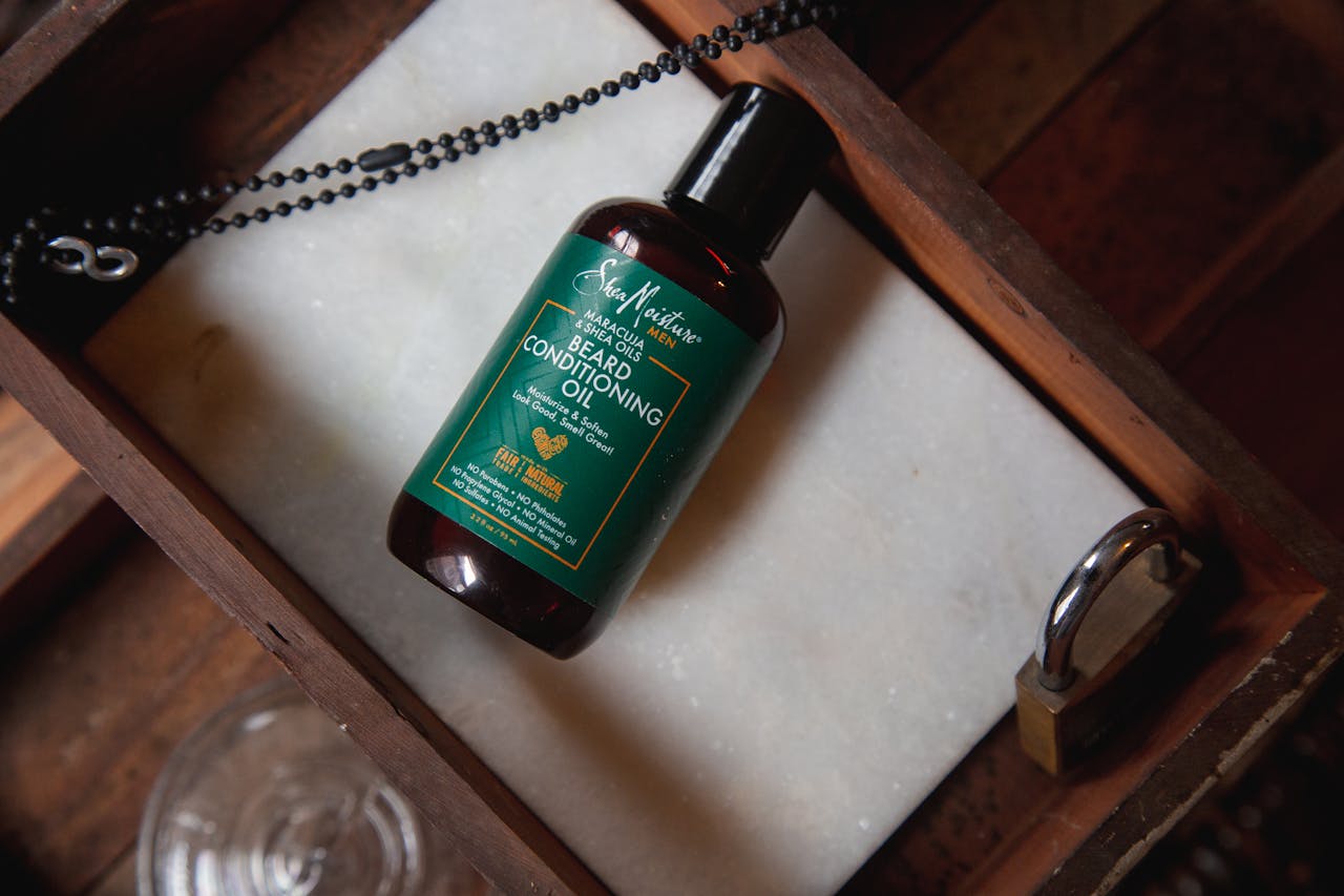 Beard conditioning oil bottle on a rustic wooden tray with a lock and chain, top view.