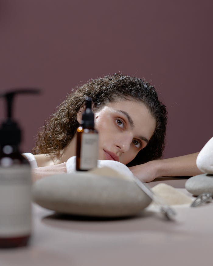 A woman with natural beauty surrounded by cosmetics and stones, creating a soothing atmosphere.